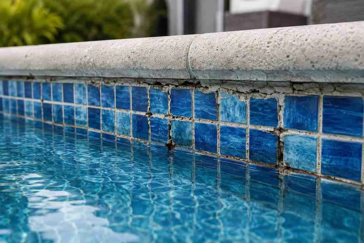 Damaged grout beside clean blue pool tile